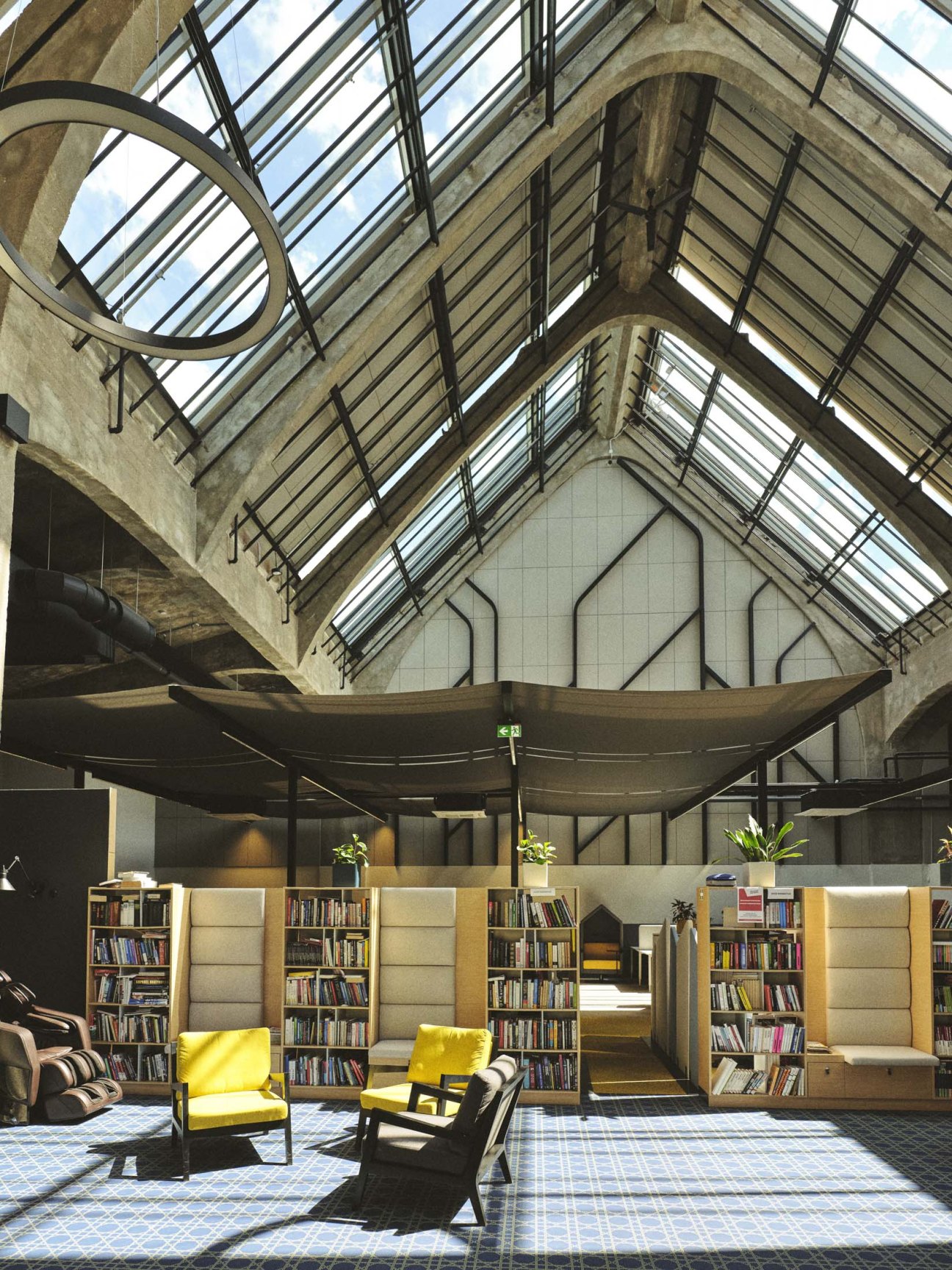 Library area with well-organized bookshelves filled with business books in an industrial office space.