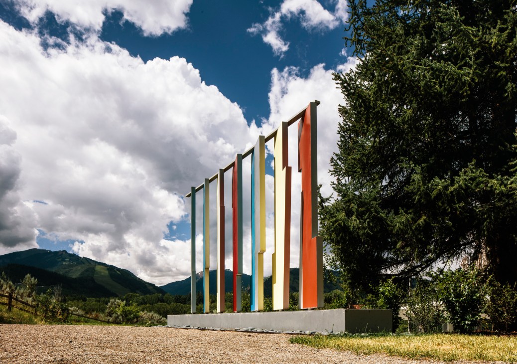 Colorful vertical metal panels forming Bayer's Kaleidoscreen sculpture at the Aspen Institute against blue sky and mountains.