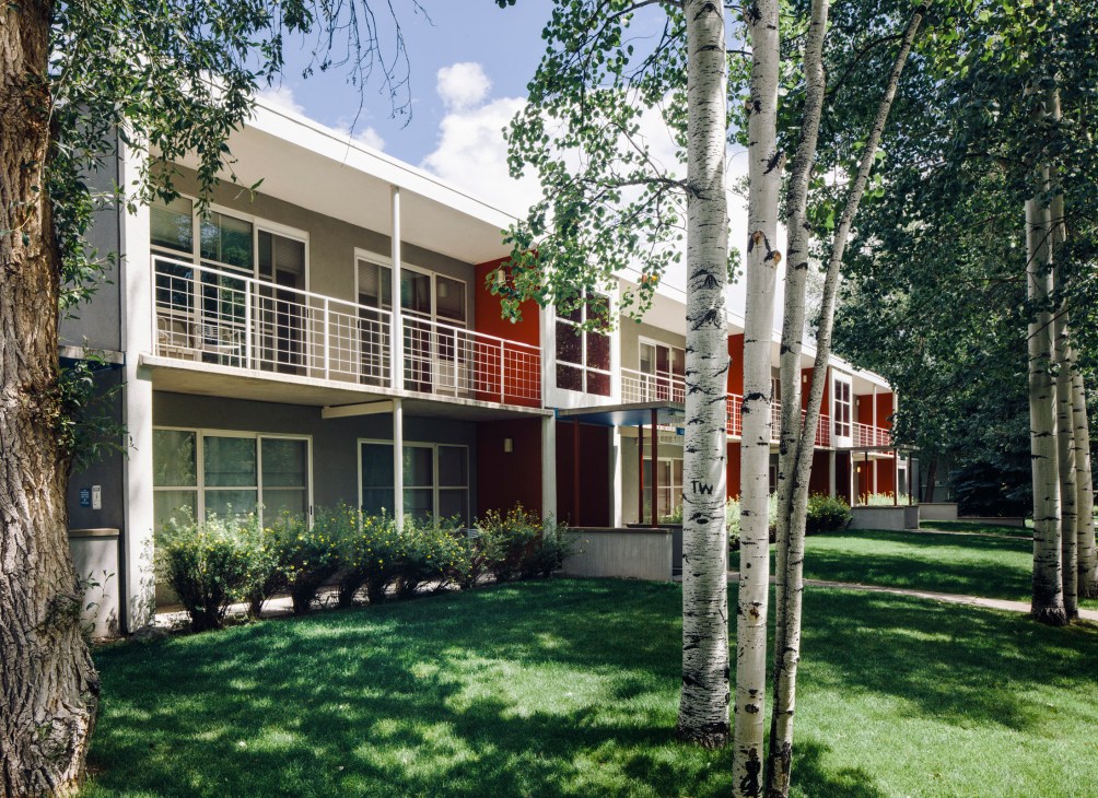 Low-rise white Bauhaus buildings with red accents nestled among birch trees and manicured lawns at Aspen Meadows.
