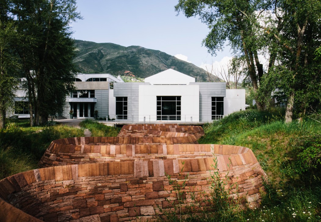 Andy Goldsworthy's Stone River artwork of stacked red stone in front of the white modernist Doerr-Hosier Center with mountains beyond.