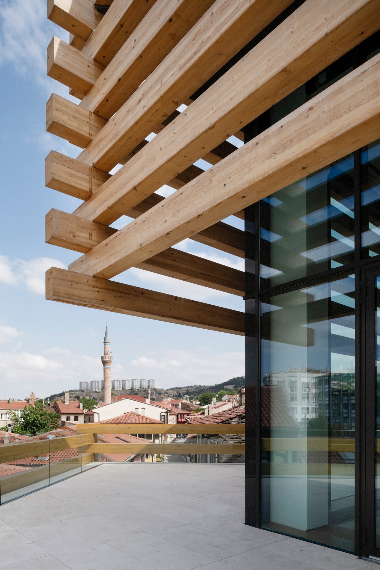 Timber beams and glass facade of Odunpazari Modern Museum with Eskisehir cityscape in background.