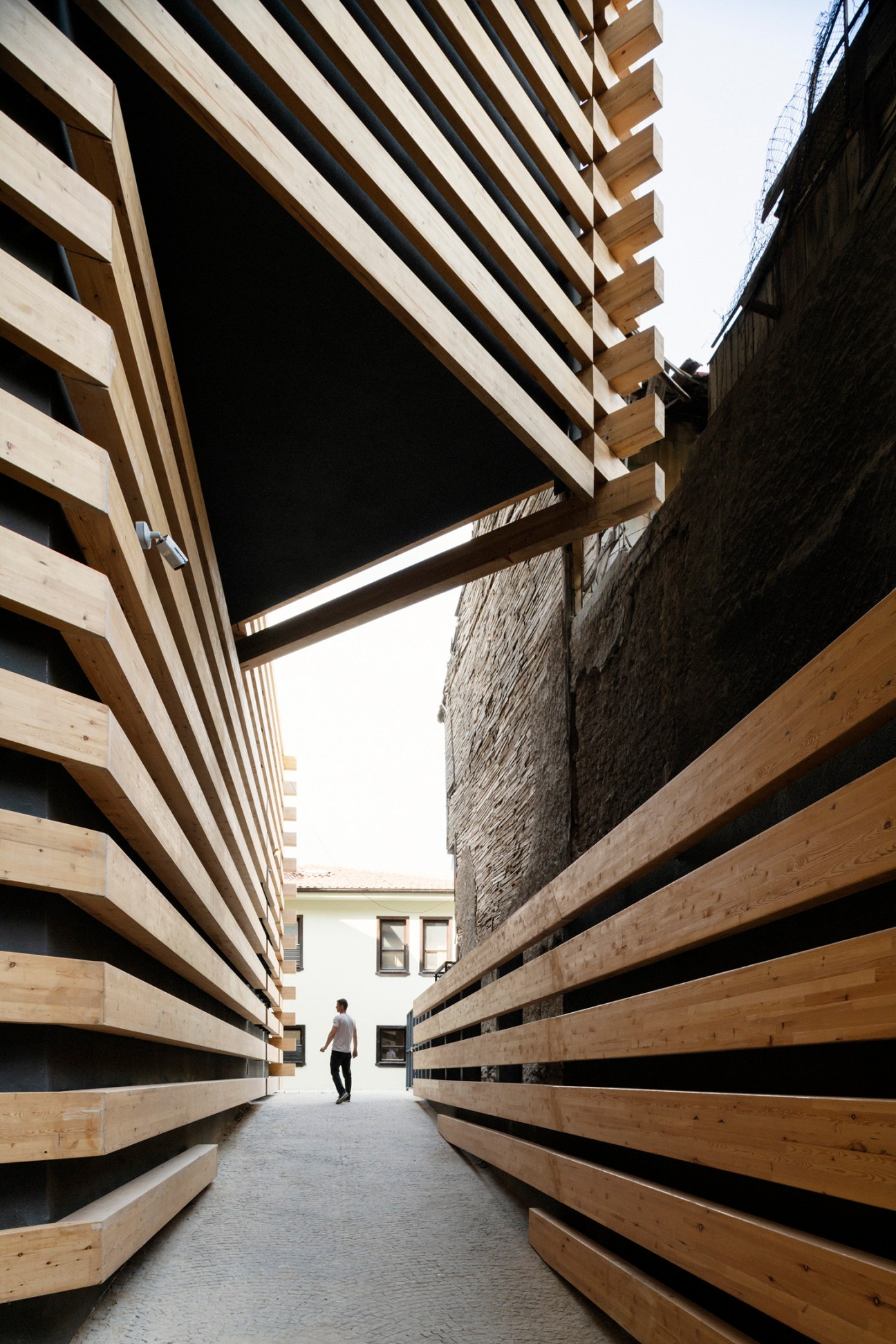 Narrow passageway between stacked timber and concrete walls of Odunpazari Modern Museum designed by Kengo Kuma.