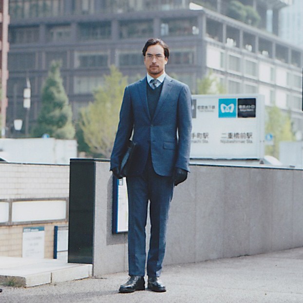 Man in blue Ermenegildo Zegna suit with Boss Black jumper standing outdoors.