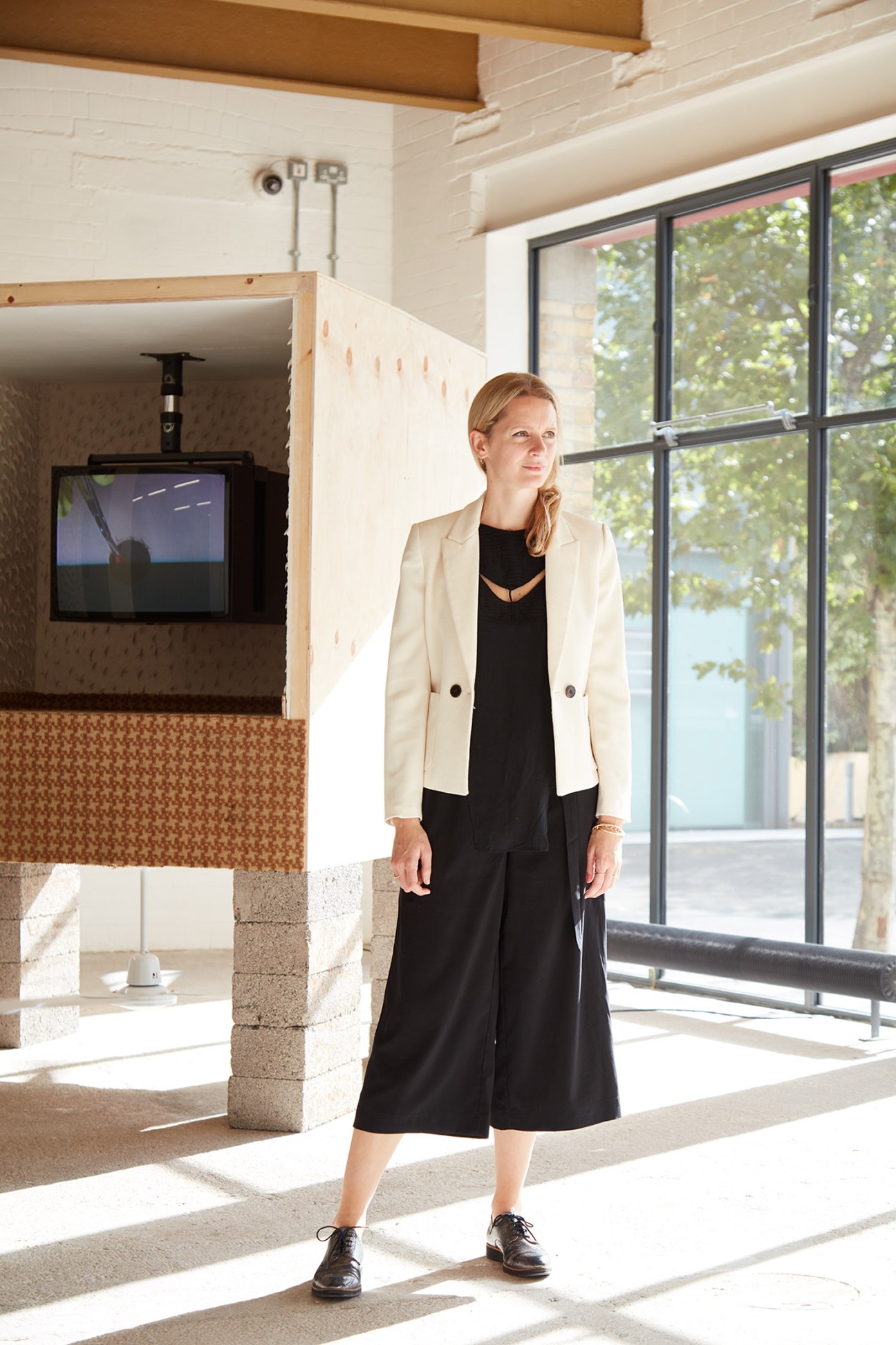 Curator Natasha Hoare standing in a gallery space with white walls and large windows