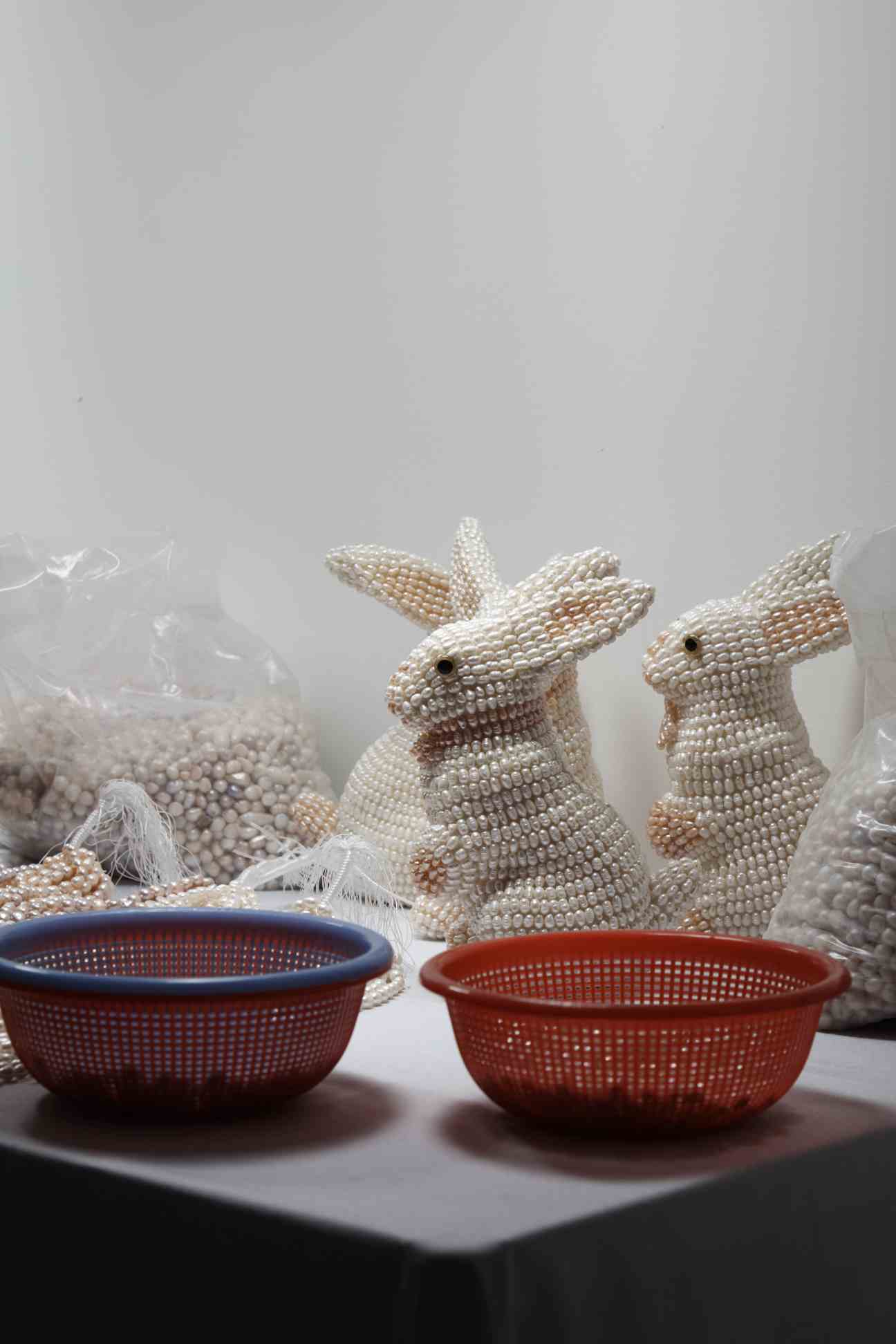 Beaded rabbit sculptures with blue and red baskets in Mika Rottenberg's 'NoNoseKnows' installation.