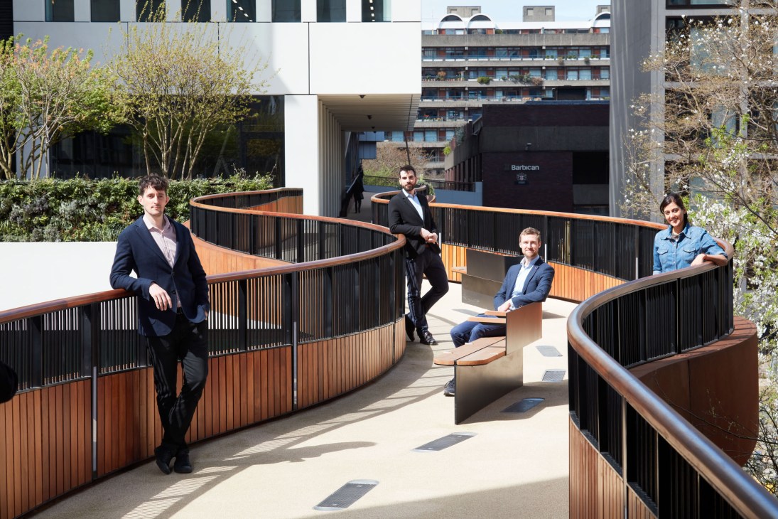 Five people posing on an elevated wooden walkway with curved railings at London Wall Place.