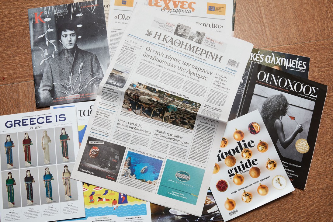 Kathimerini's Sunday newspaper edition displayed with various supplements and magazines on a wooden surface.