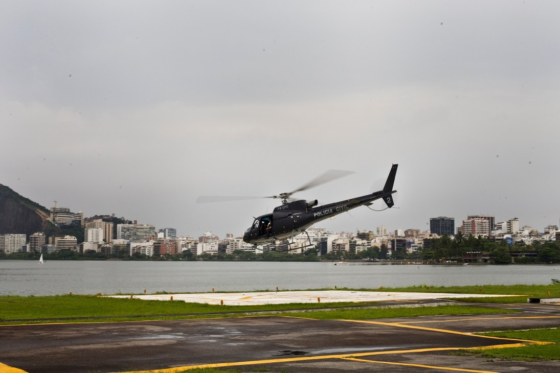 Black UH-1H Huey II helicopter taking off from helipad near Lagoa Rodrigo de Freitas in Rio de Janeiro.