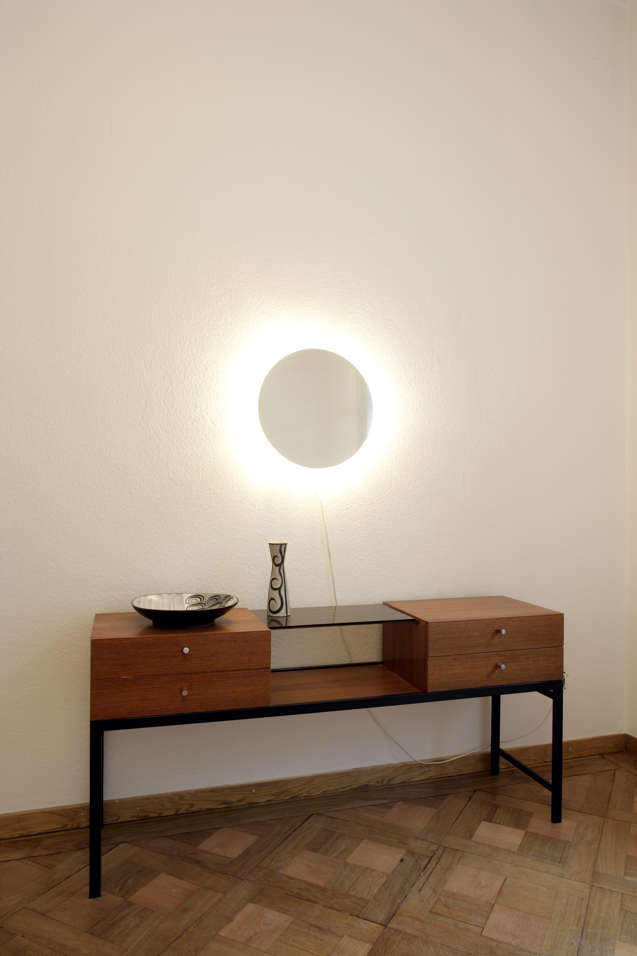 Mid-century modern wooden desk with metal legs and circular wall light in Zum Guten Glück B&B.