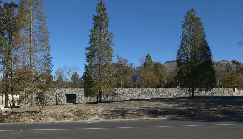 Low-lying granite building with dark entrance nestled among tall trees in a national park landscape.