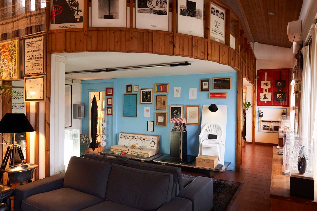 Artist apartment at Bonotto factory with blue walls displaying framed artworks, vintage furniture, and creative workspace.