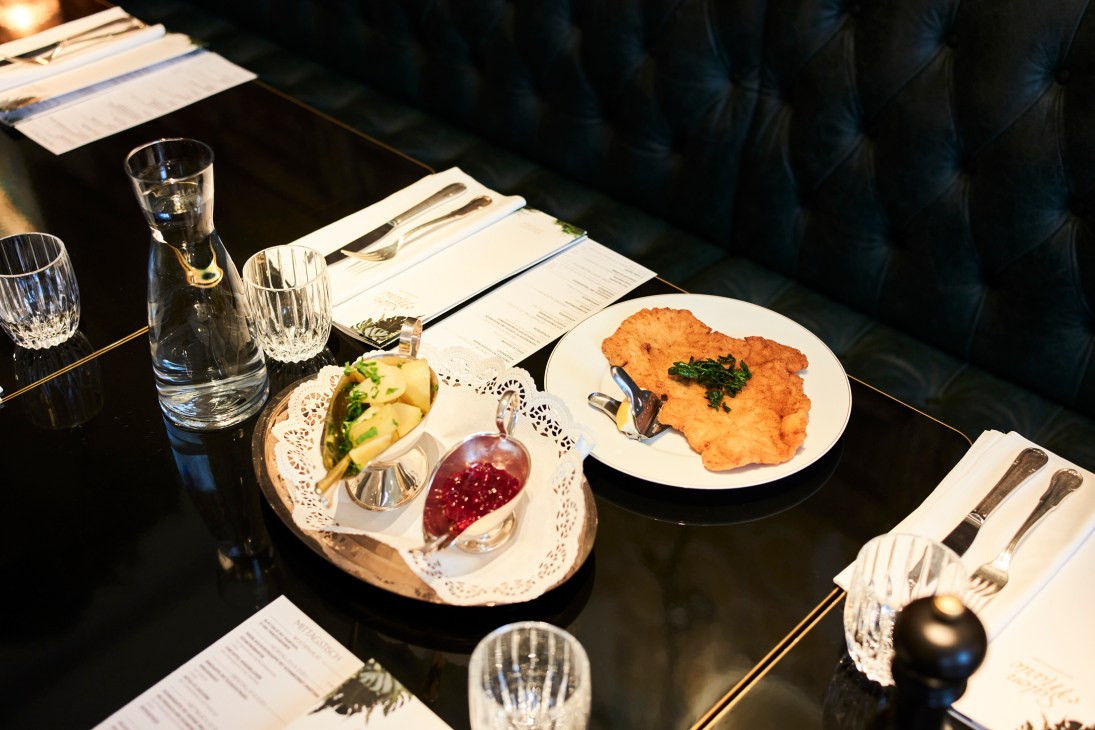 Elegant restaurant table setting with schnitzel, accompaniments, crystal glasses, and fine dining presentation
