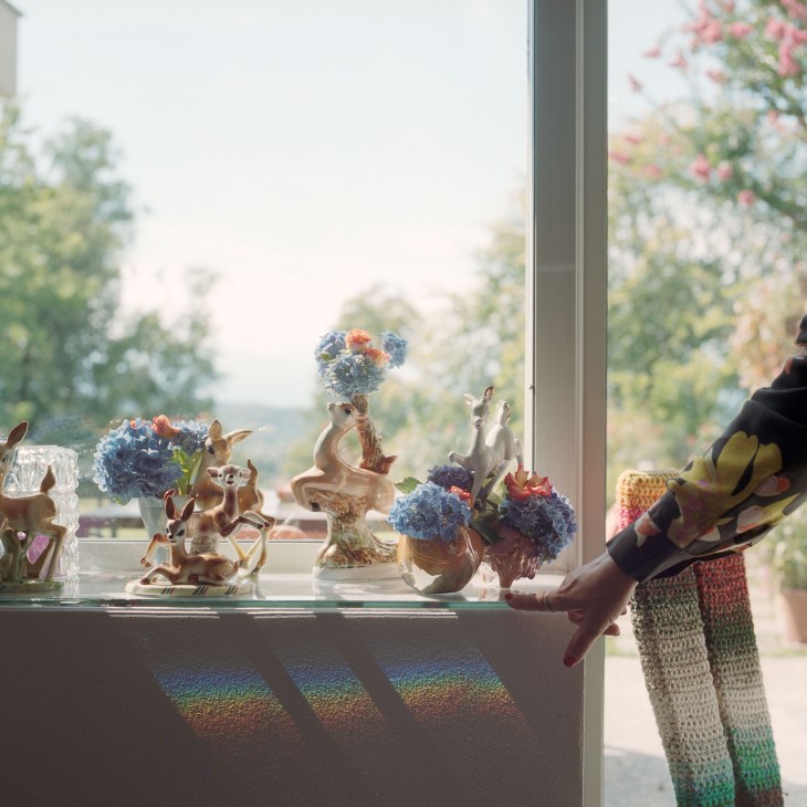 Vintage ceramic Bambi vases with colorful flowers displayed on a windowsill overlooking a pastoral landscape.
