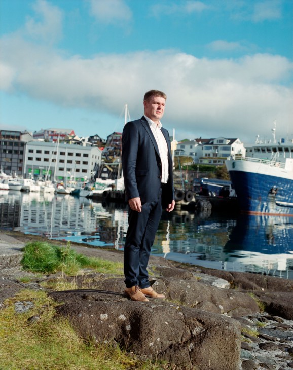 Aksel V Johannesen, prime minister of the Faroe Islands, stands on rocks overlooking Tórshavn harbour.