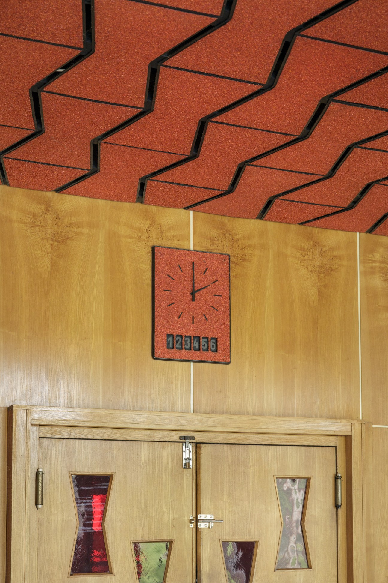 Milchbar restaurant interior with wooden walls, red clock, and vintage glass-front cabinets