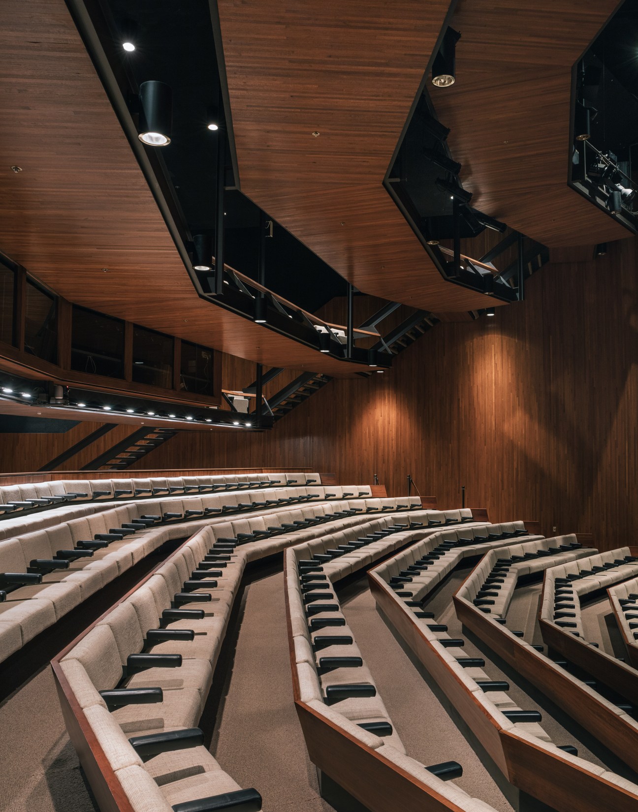 Interior view of John Deere auditorium with curved rows of beige seats and wood-paneled ceiling with skylights.