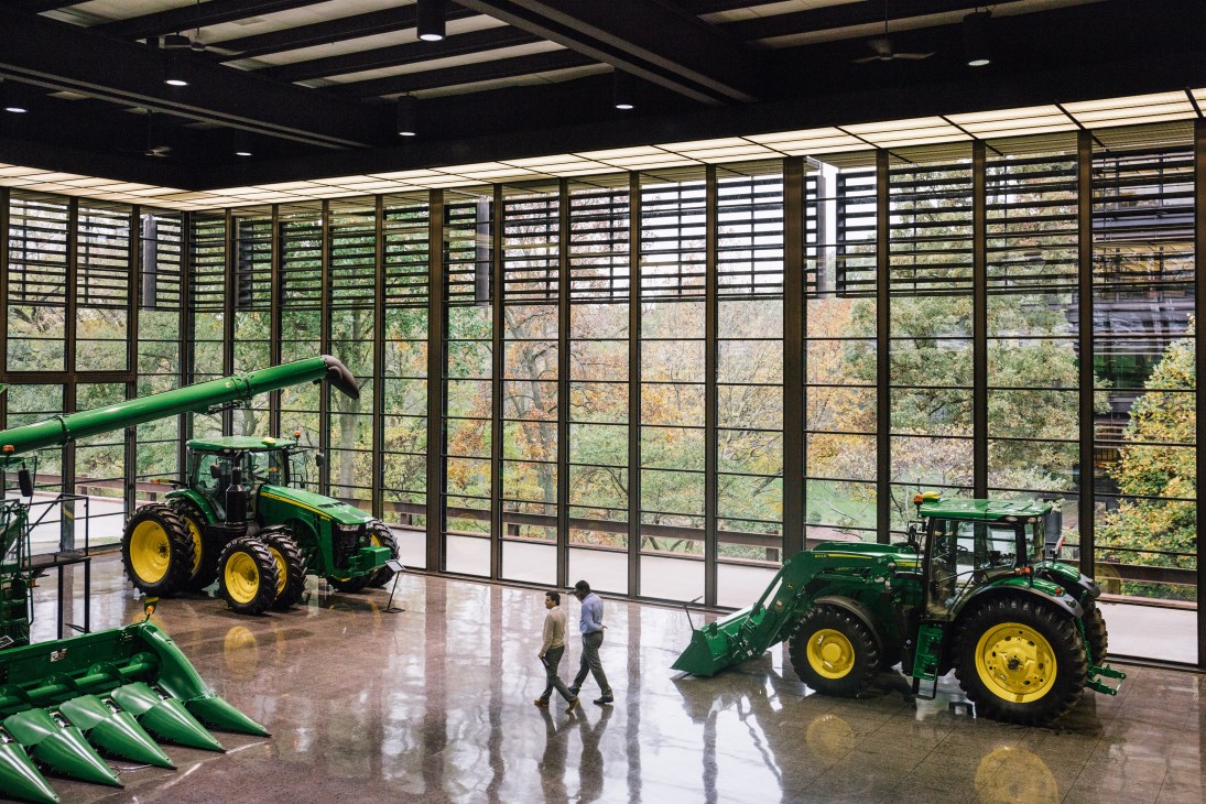 John Deere Display Floor featuring green and yellow tractors with large windows overlooking rural landscape.