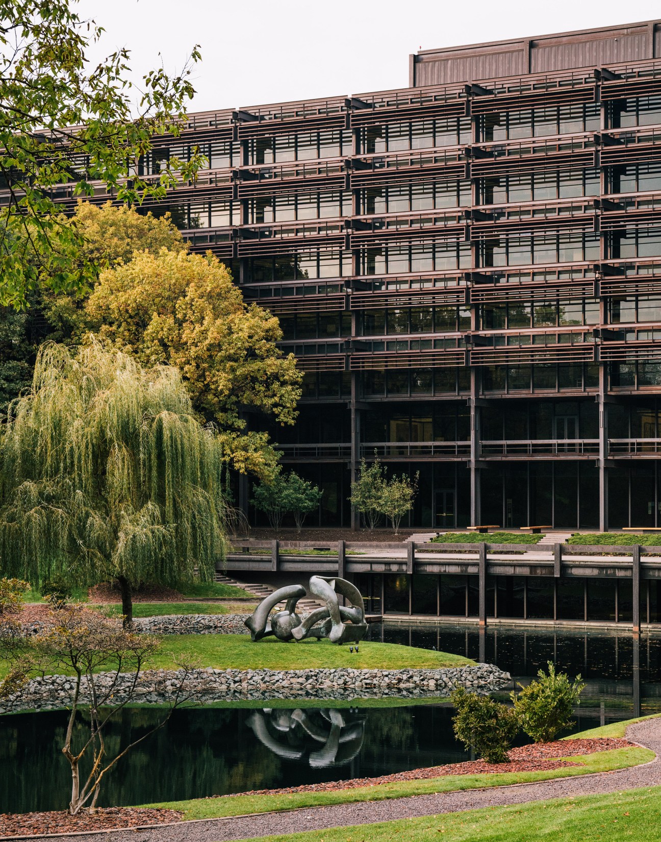 Henry Moore sculpture 'Hill Arches' displayed on landscaped grounds with pond beside John Deere headquarters building.