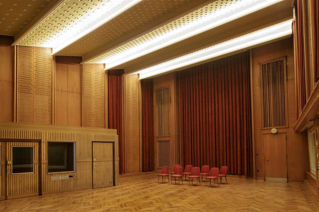 Interior of a professional recording studio with wood paneling, acoustic treatment, red curtains, and studio lighting.