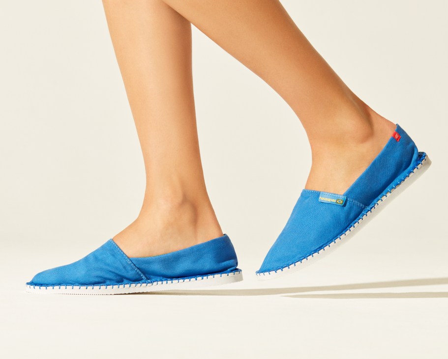 Model wearing blue Havaianas espadrilles with white sole against neutral background.