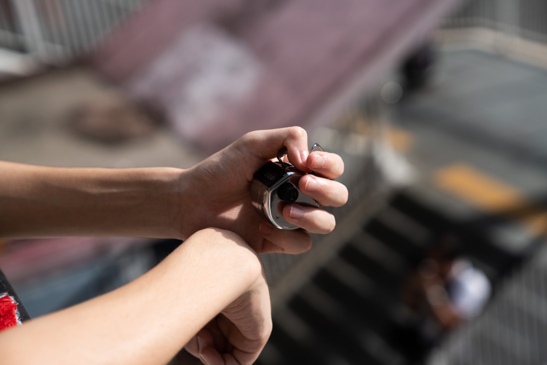 Hand holding a silver tally counter used to count protest marchers.