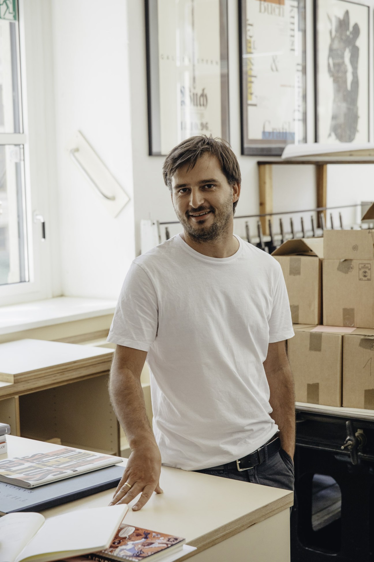 Johannes Oestringer stands in HGB's printing workshop surrounded by letterpress equipment.