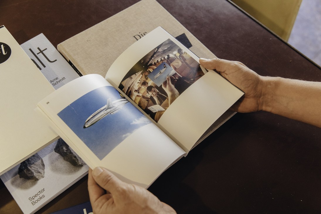 Hands flipping through a publication designed by Arc studio, showing interior pages with photography and typography.