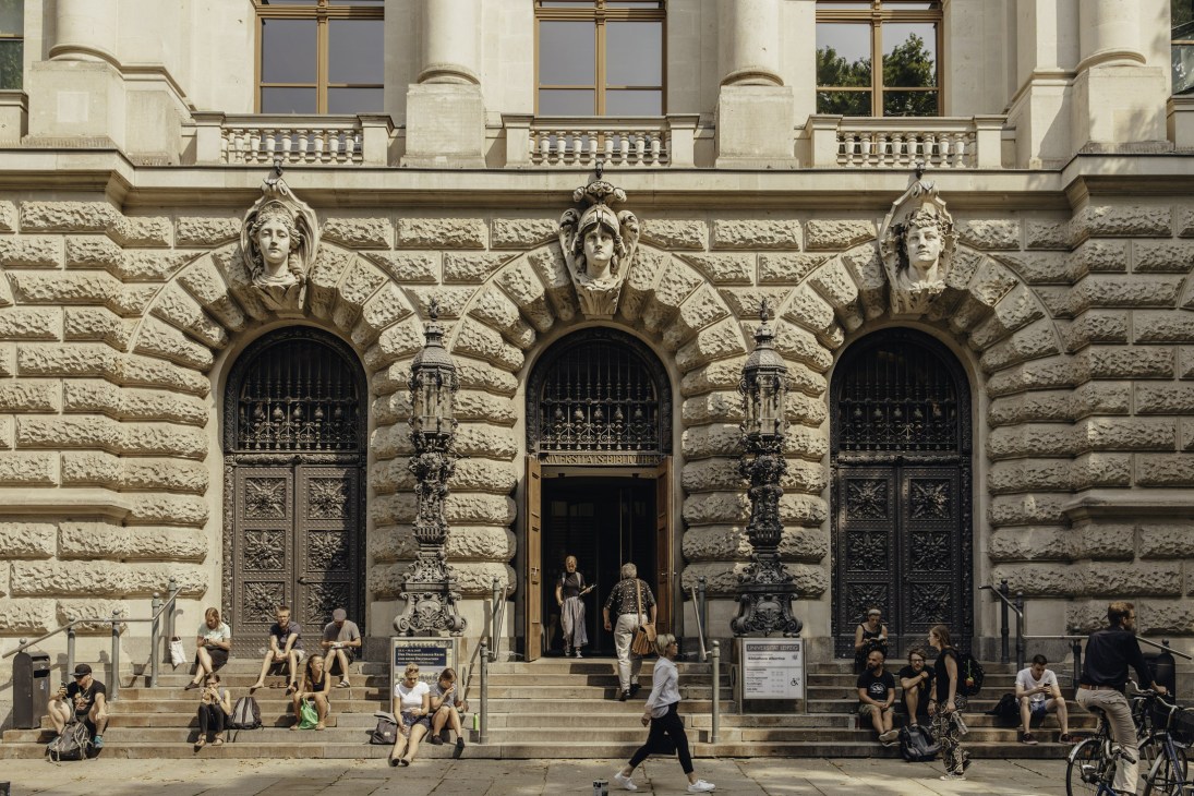 People relaxing on the steps outside Leipzig's university library on a sunny day.