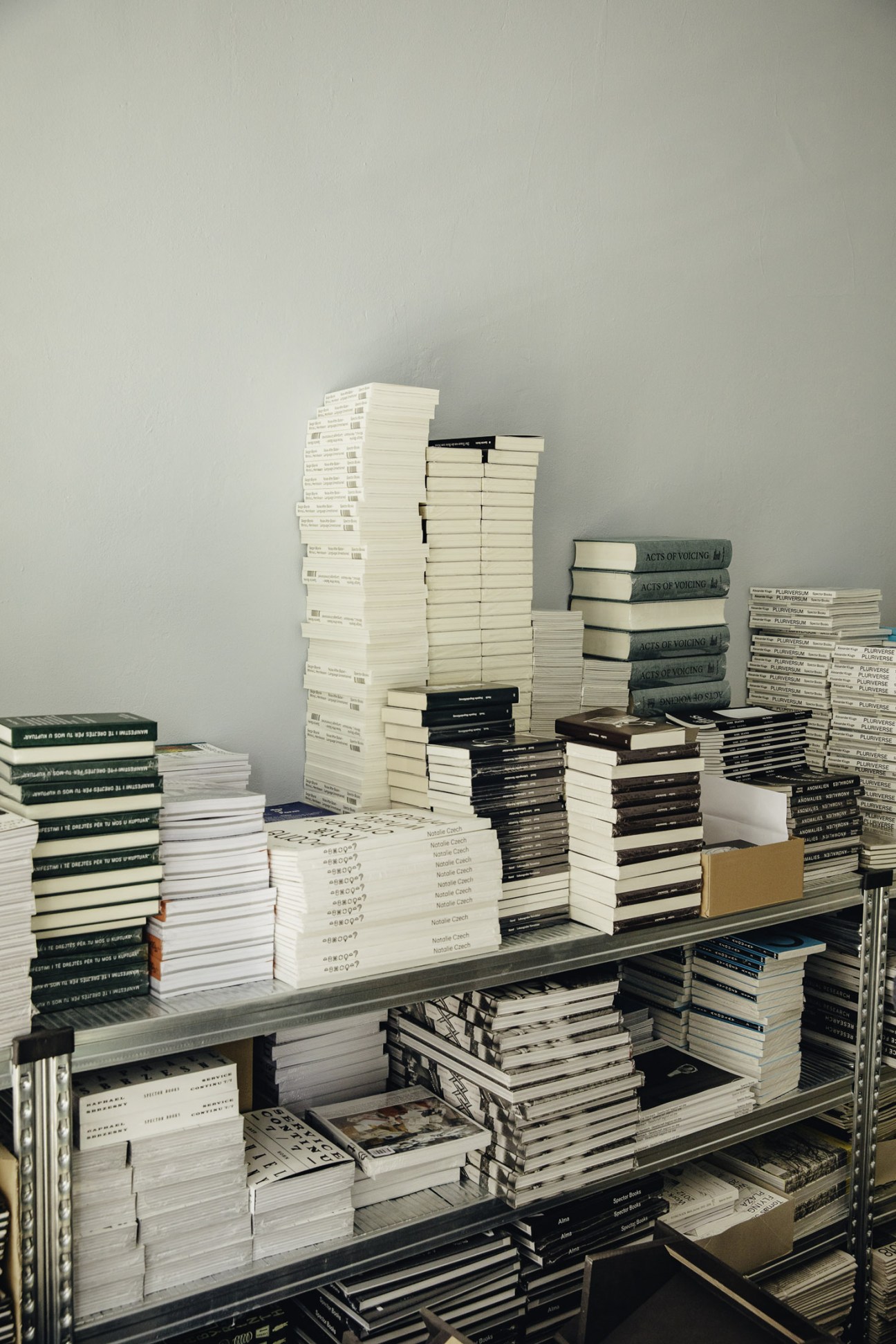 Tall metal shelving racks stacked with white and black bound publications in Spector Books' office.