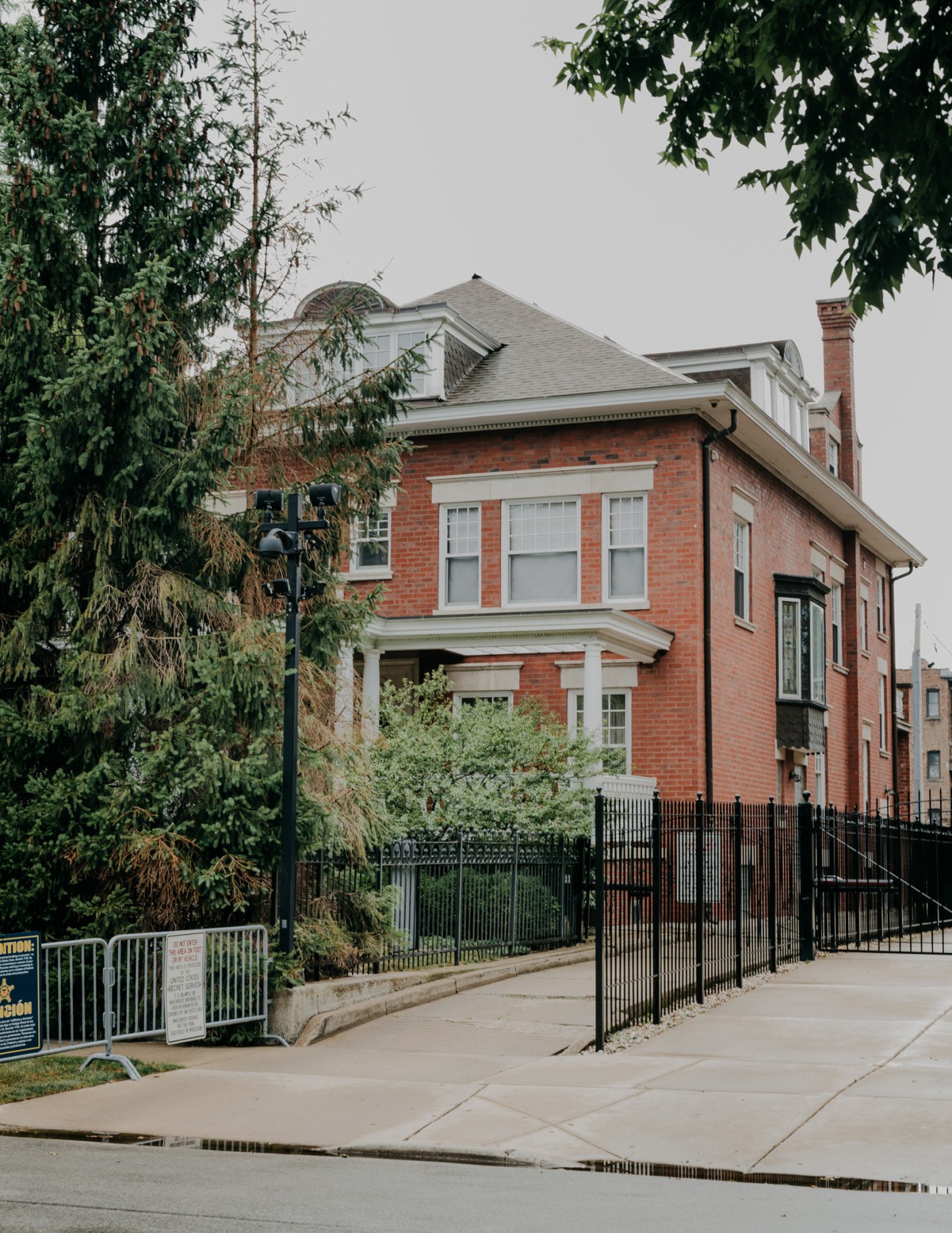 Red brick two-story house with white trim and black iron fence in Chicago's Hyde Park neighborhood.