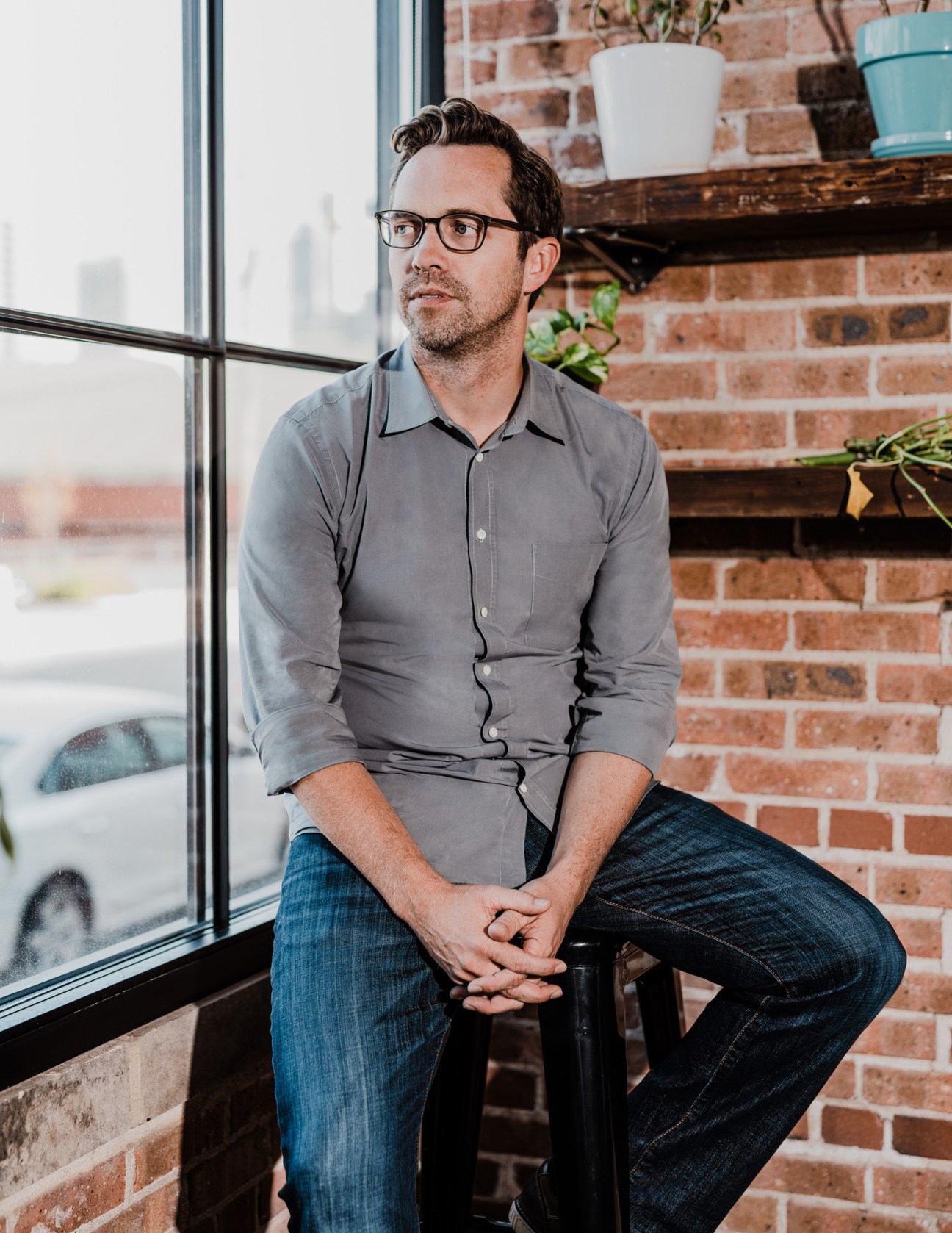 270 Strategies co-founder Jeremy Bird sitting by a window in an office with exposed brick walls.