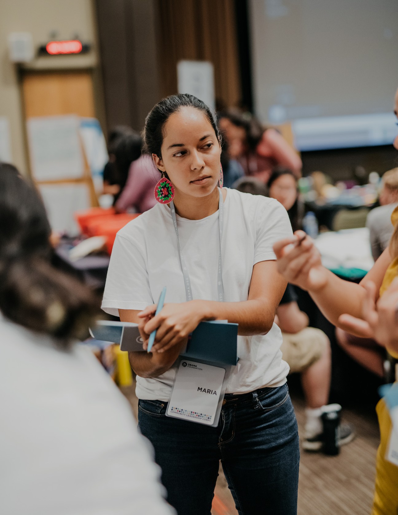 Young woman at Obama Foundation Community Leadership Corps bootcamp wearing name badge and holding materials.
