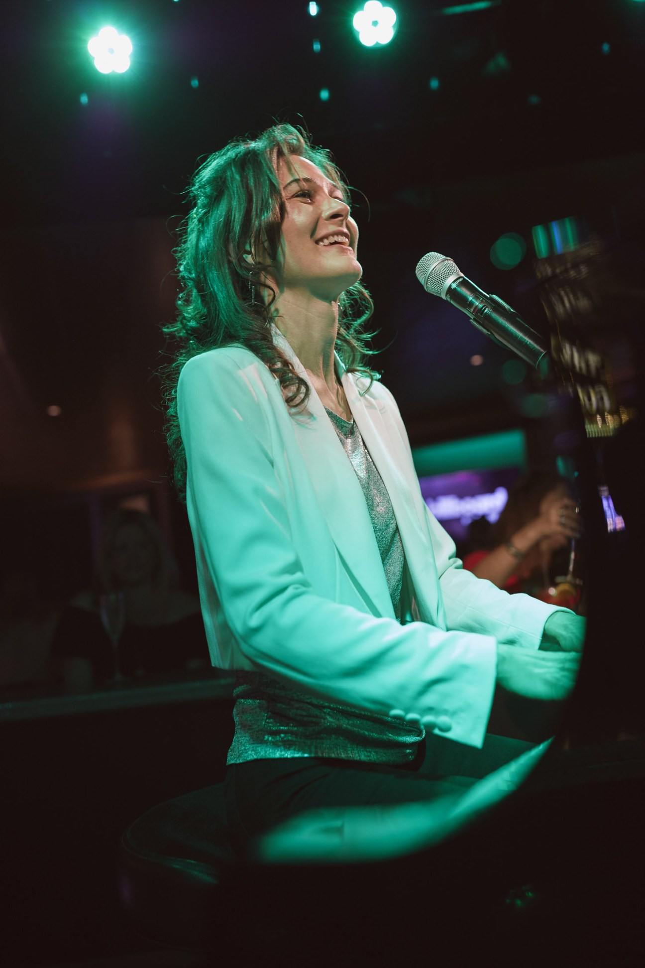 Singer performing at microphone under green stage lighting in Billboard Onboard bar.