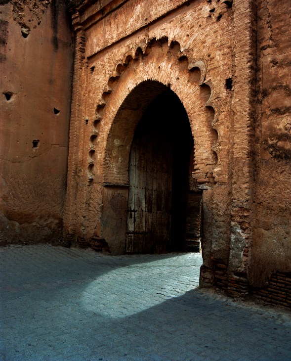 Sunlight streaming through an ornate arched doorway with scalloped details in Taroudant's medina walls.