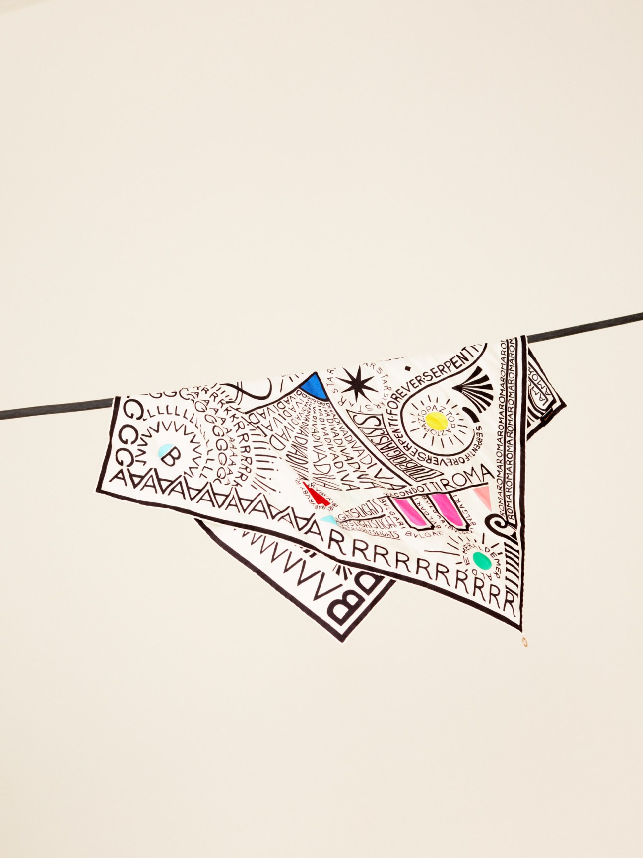 Colorful patterned scarf with geometric designs, text elements, and bright accents in pink, blue, and yellow.