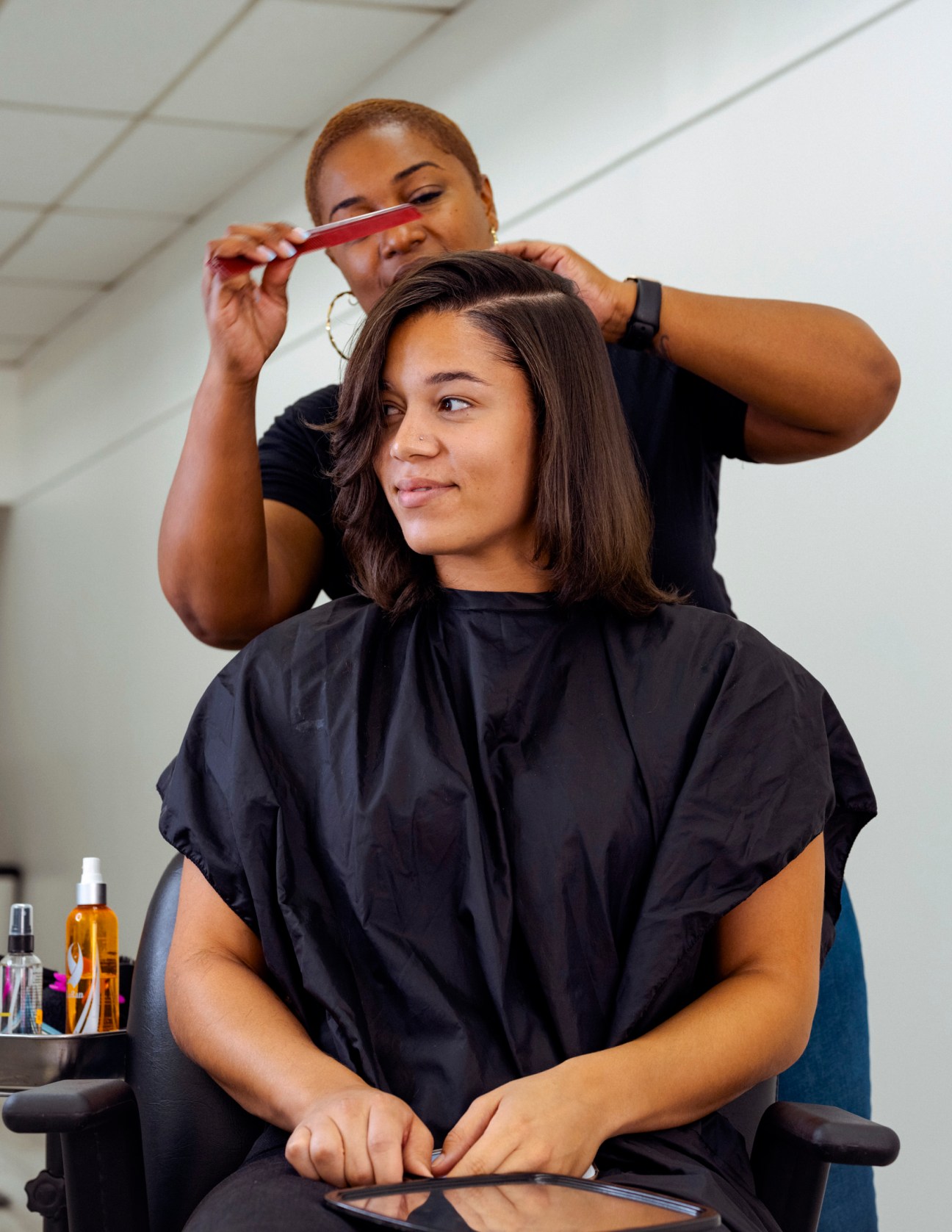 Stylist Nina Simone applying a silk press to client Erika's hair in a salon.