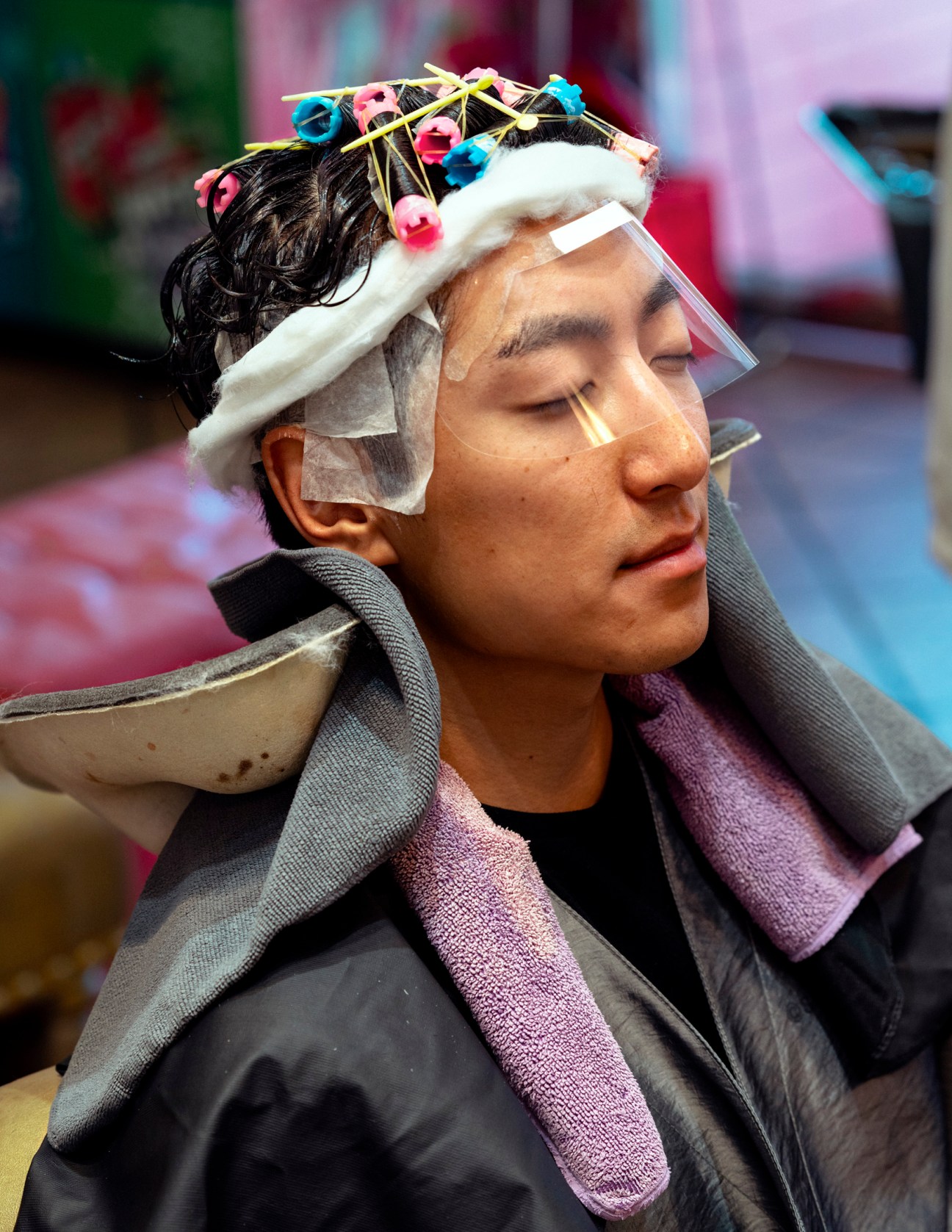 Eddie wearing hair rollers and styling clips during his first perm treatment at a salon.