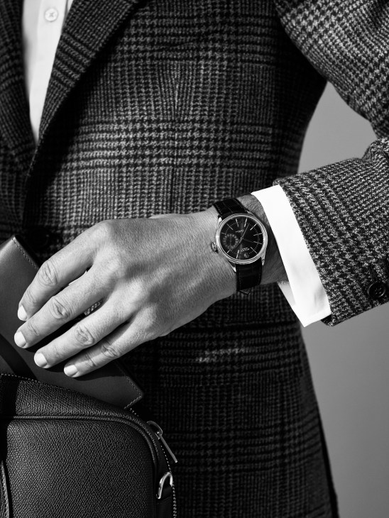 Close-up of a man's wrist wearing a Rolex Cellini Date watch with black leather strap, styled with an Orazio Luciano jacket and Dunhill shirt.