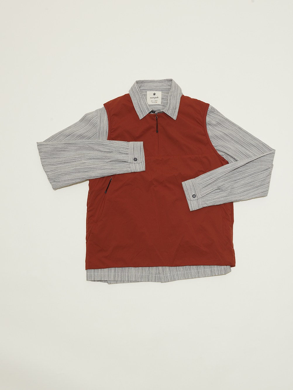 2L Octa vest in rust red worn over gray striped Shijira shirt