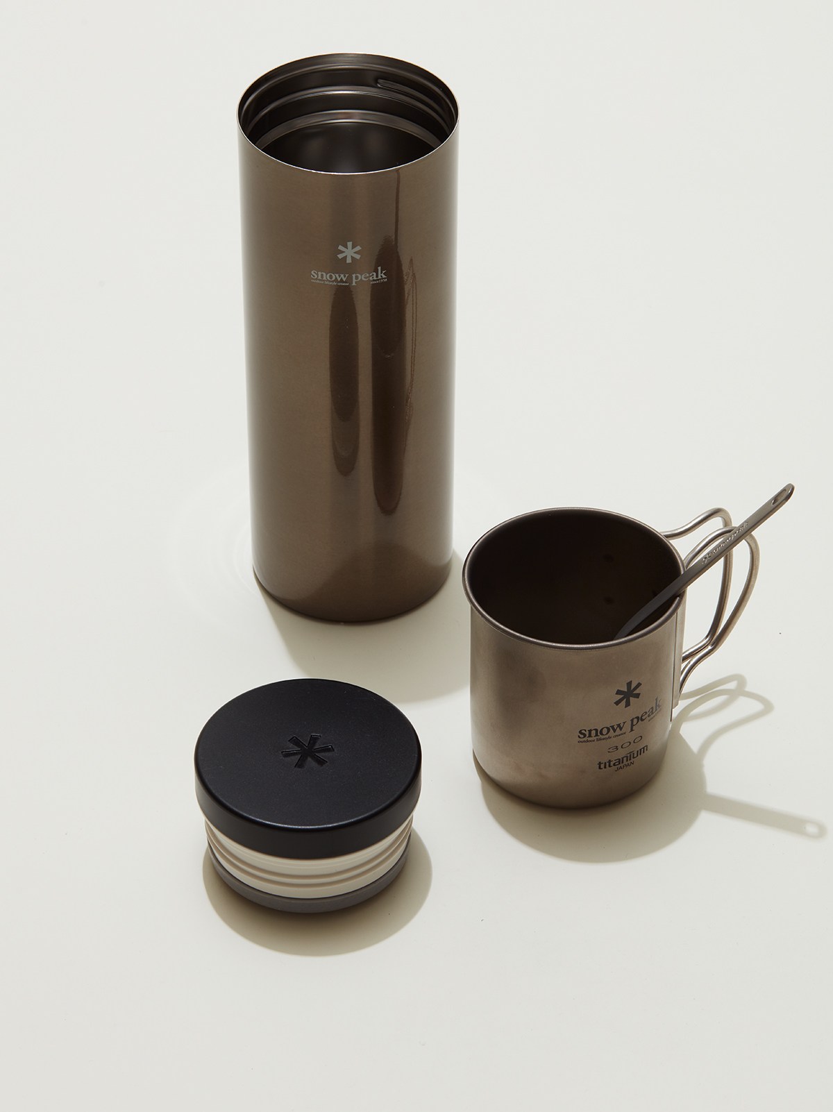 Snow Peak Kanpai bottle, titanium mug and titanium spork arranged on white surface