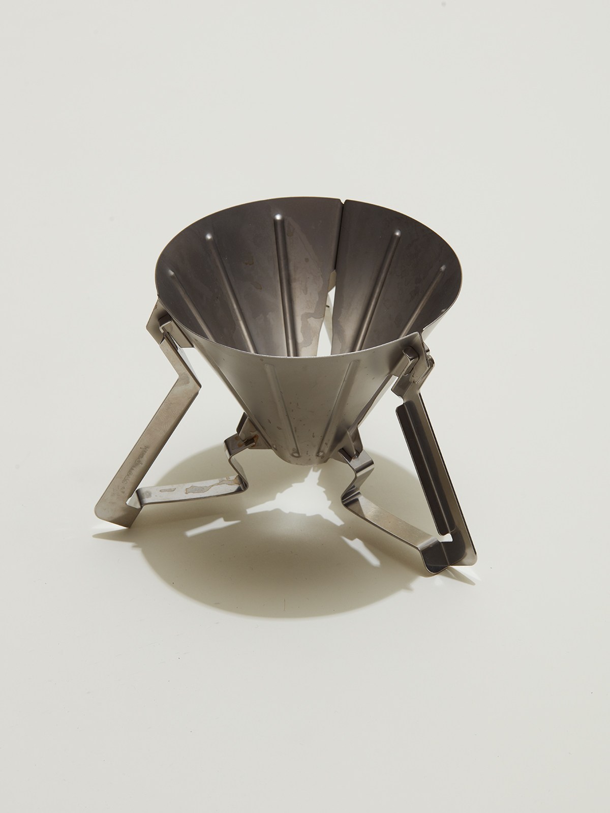 Stainless steel collapsible coffee dripper with cone-shaped filter and folding legs on white background