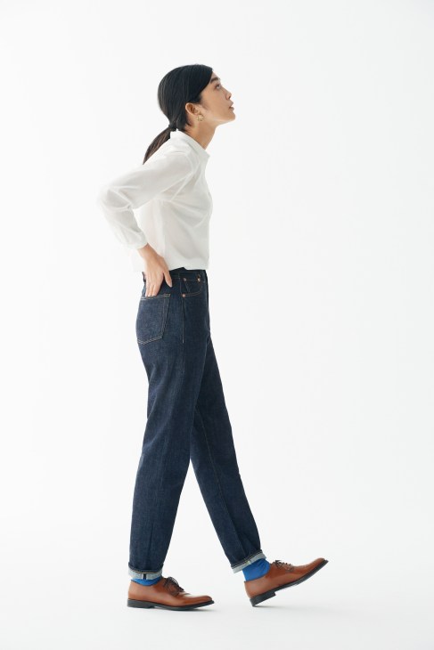Woman in profile wearing a white Leno shirt, dark jeans, brown Church's shoes, and Maria La Rosa socks.