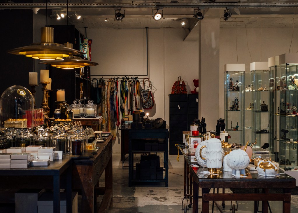 Interior of 21PR Concept Store in Lisbon displaying clothing, accessories, homeware and decorative items on display tables and shelving.