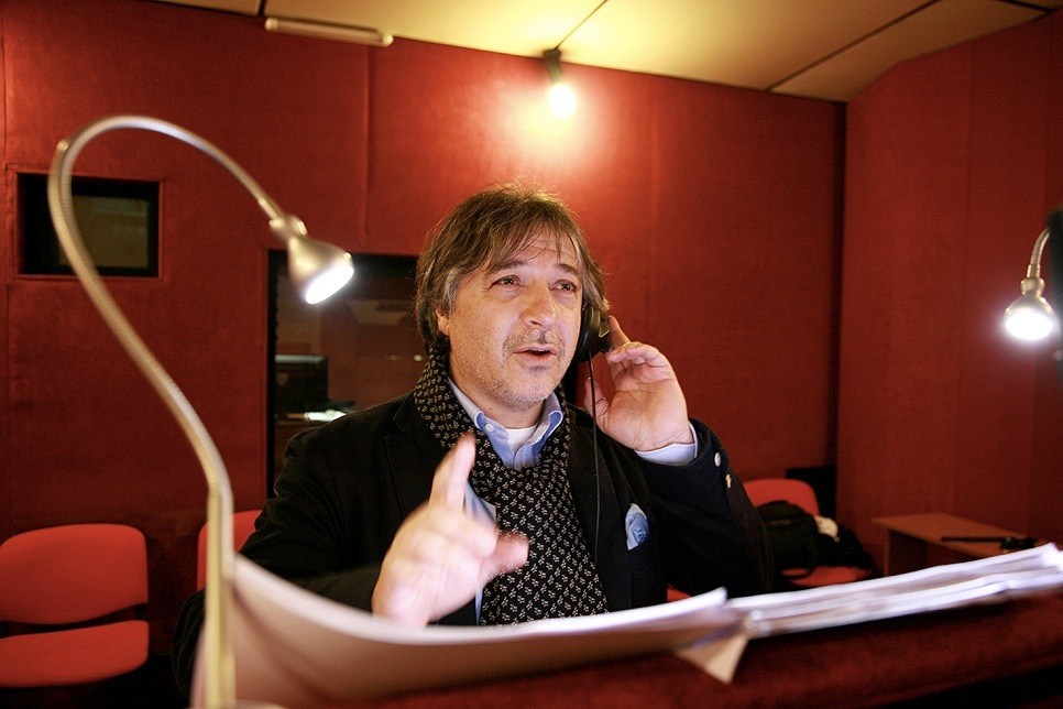Massimo Rossi, Italian dubbing actor for Sean Penn, wearing headphones in a red recording studio