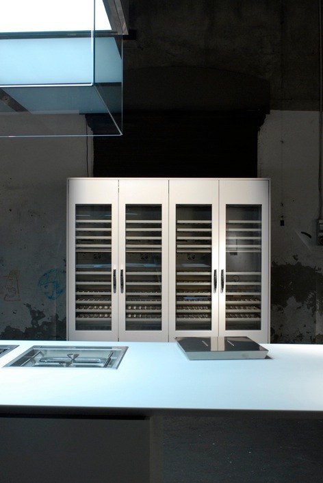 White kitchen storage system with glass-front cabinets displaying shelving, designed by Piero Lissoni for Boffi.