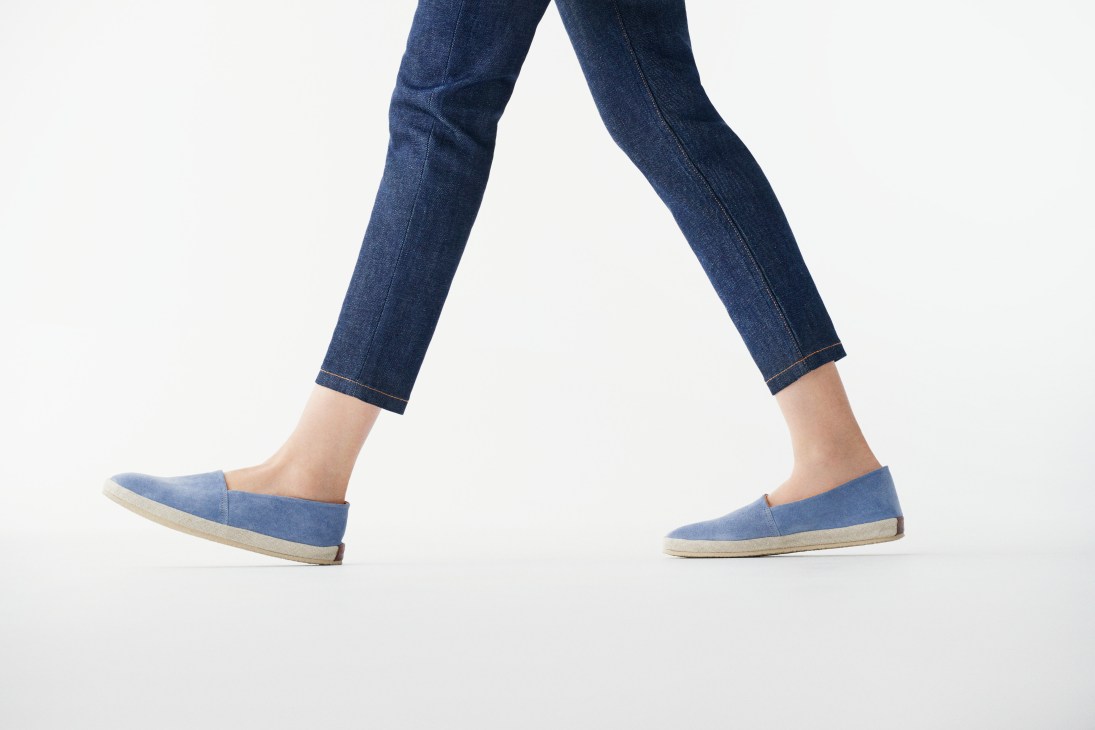 Person wearing dark blue APC jeans and Ludwig Reiter blue suede slip-on shoes against white background.