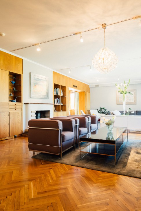 Modern living room with brown leather chairs, black coffee table, wooden cabinetry, and crystal pendant light at Villa Granebo.
