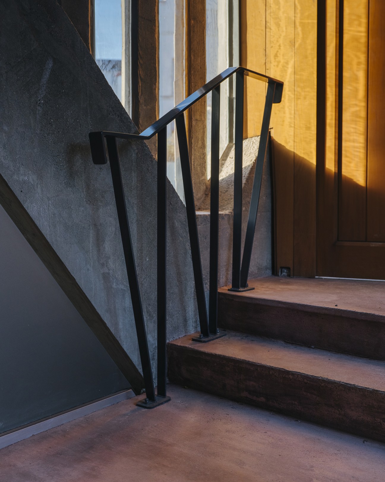 Modern black metal handrail next to concrete staircase with yellow curtains and ocean view