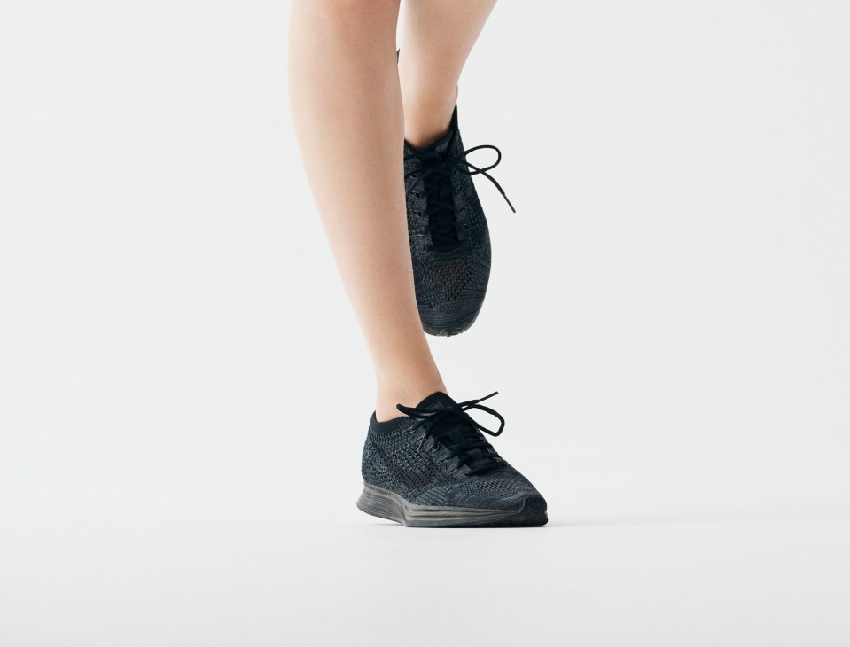 Close-up of black knit Nike trainers on a person's feet against a white background.