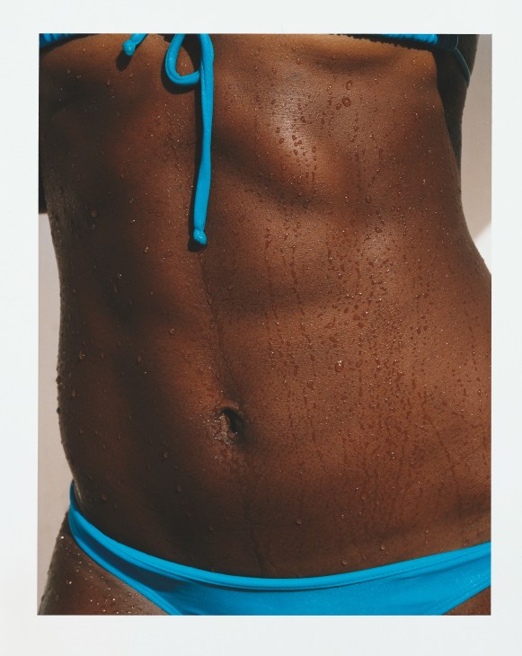 Shirtless athlete with wet skin wearing blue swim briefs and drawstring.